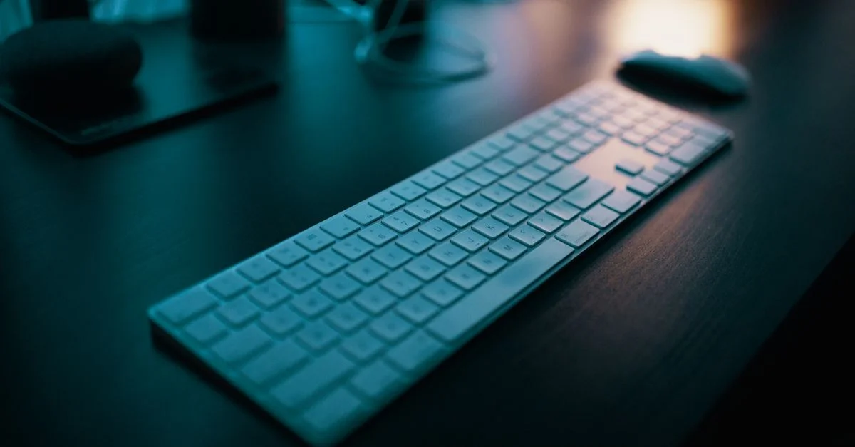 Un clavier sans fil moderne posé sur un bureau élégant, éclairé par un éclairage d'ambiance dans un cadre de bureau technologique.