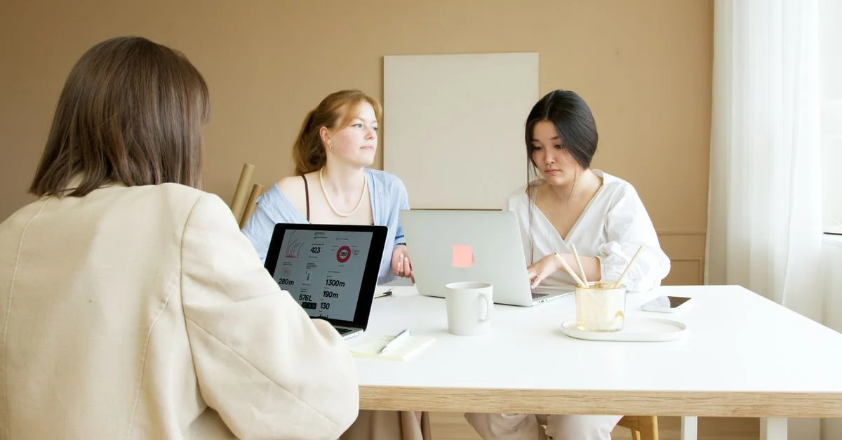 Trois collègues planifient et réfléchissent avec des ordinateurs portables dans un bureau moderne lumineux.