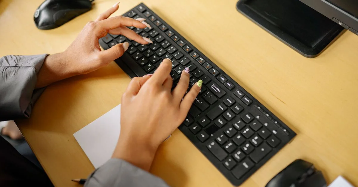 Mains tapant sur un clavier dans un environnement de bureau, vu d'en haut.
