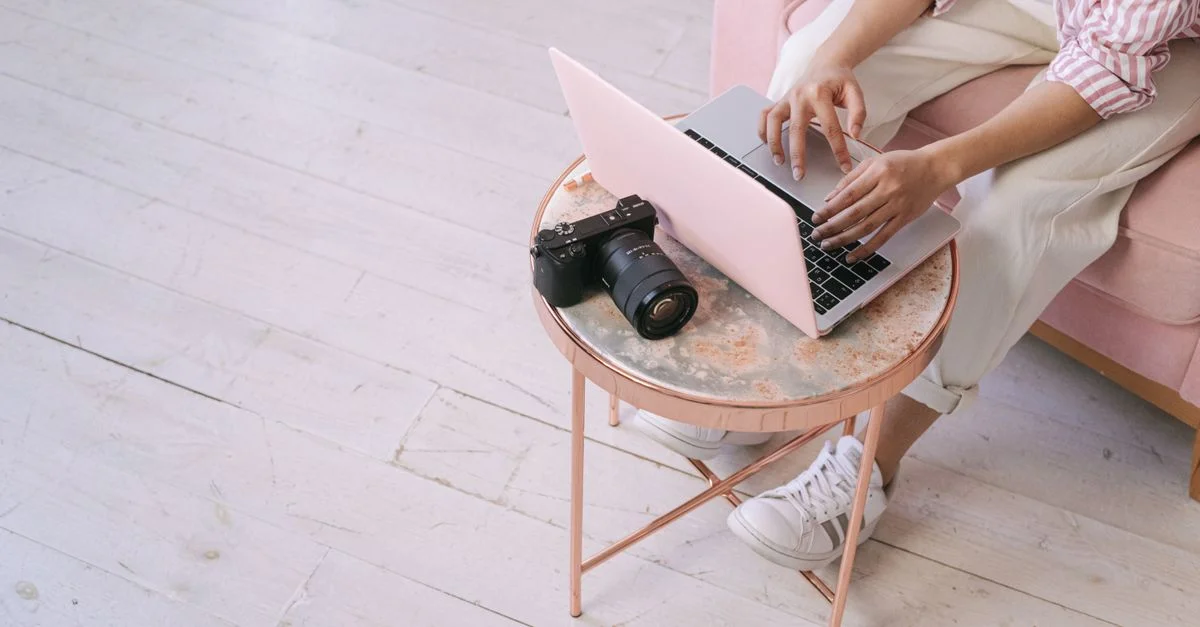 Un adulte utilisant un ordinateur portable à la maison, avec une caméra sur une table ronde, illustrant un environnement de travail à domicile.